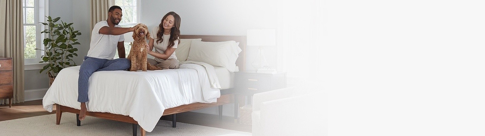 Man, woman, and dog sitting on a bed